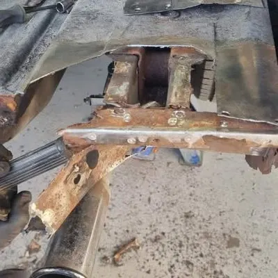 Rusted mounting brackets and floor section cut away from the Mustang’s underbody