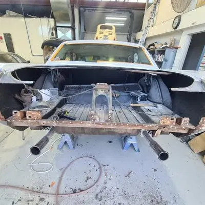 Mustang boot area stripped out on stands, showing the rusted rear floor before repair