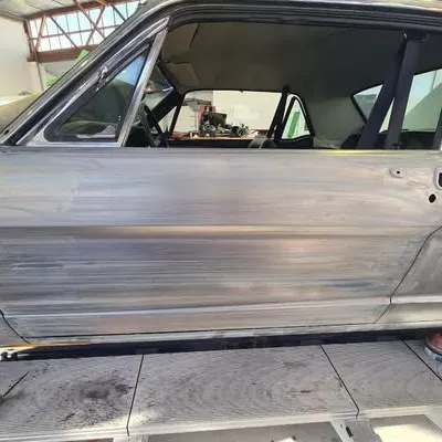Side of the Mustang stripped to bare metal from front to rear