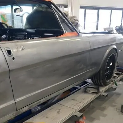 Door and rear quarter in bare metal, car on the workshop jig