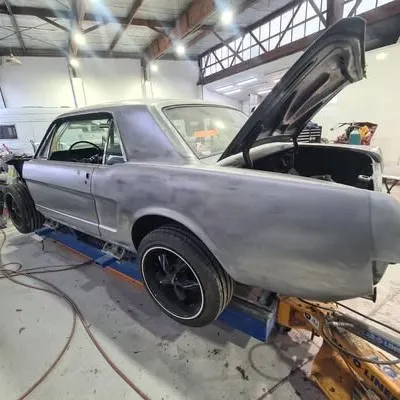 The whole Mustang body in bare metal on the workshop jig, bonnet open