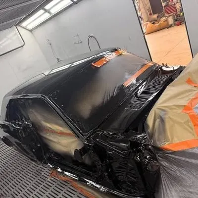 Front of the Mustang freshly painted gloss black in the spray booth, engine bay masked
