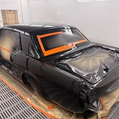 Gloss black paint reflecting the booth lights, with the glass still masked